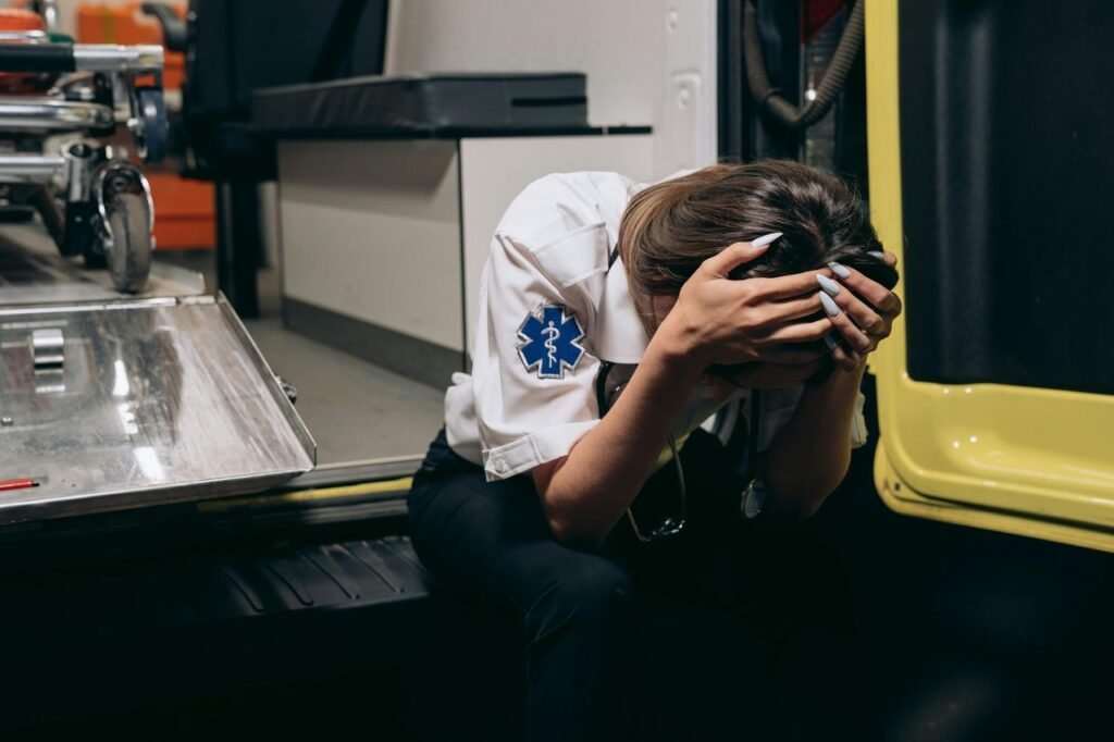 EMT in distress sitting inside an ambulance, head in hands signifying potential trauma that requires specialist trauma counselling